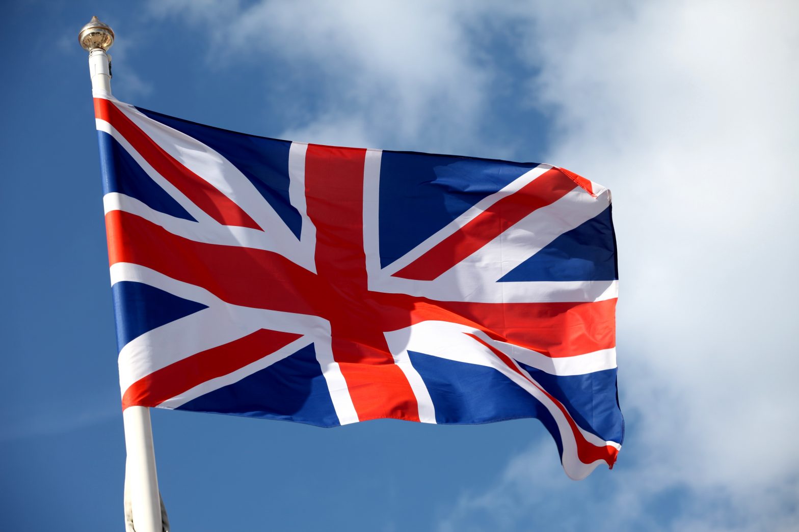 Union jack flag on pole with sky in background