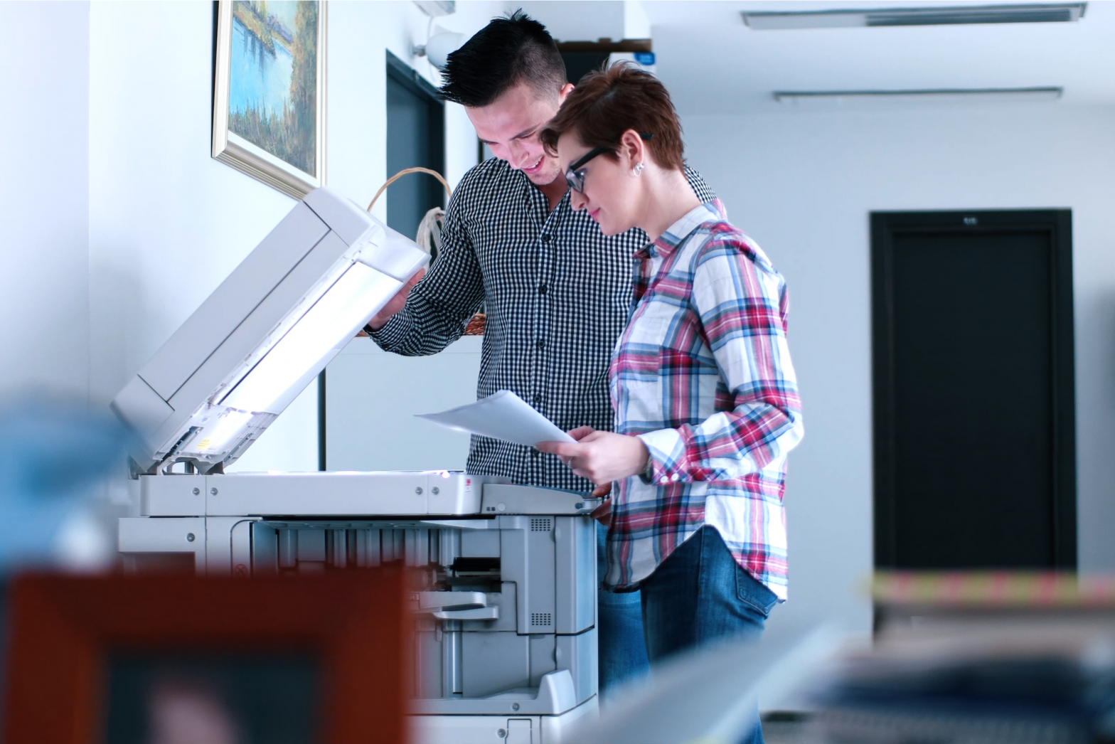 a man and a woman looking at a printer