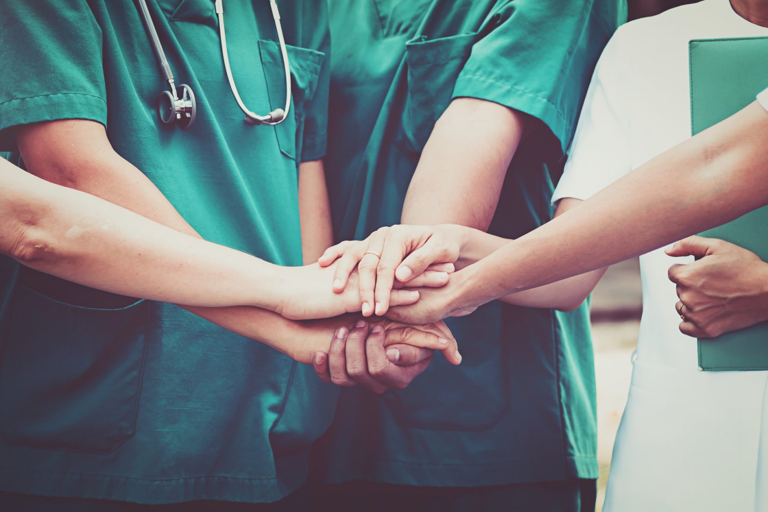 people in scrubs joining hands