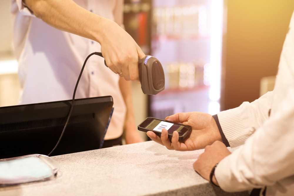 Checkout operator scanning payment barcode on smartphone