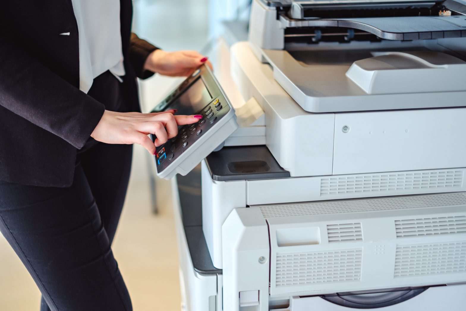 the hands of a woman pressing a button on a printer
