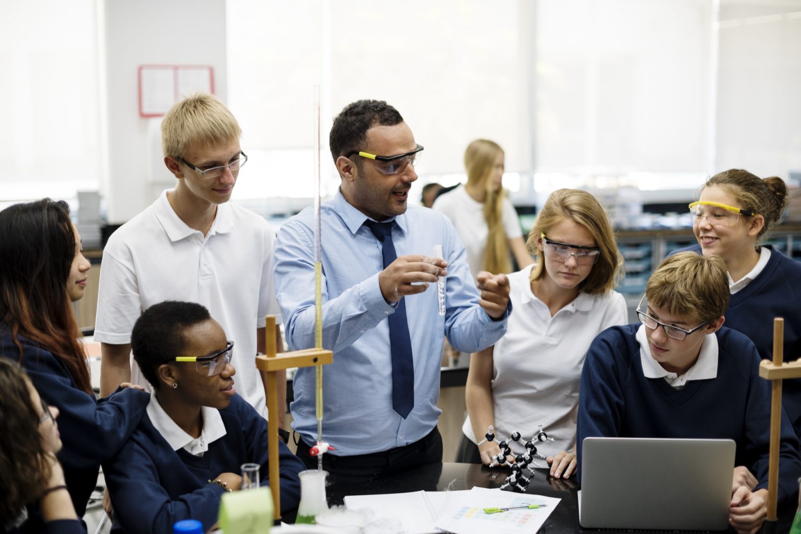 school teachers surrounded by children doing a science experiment