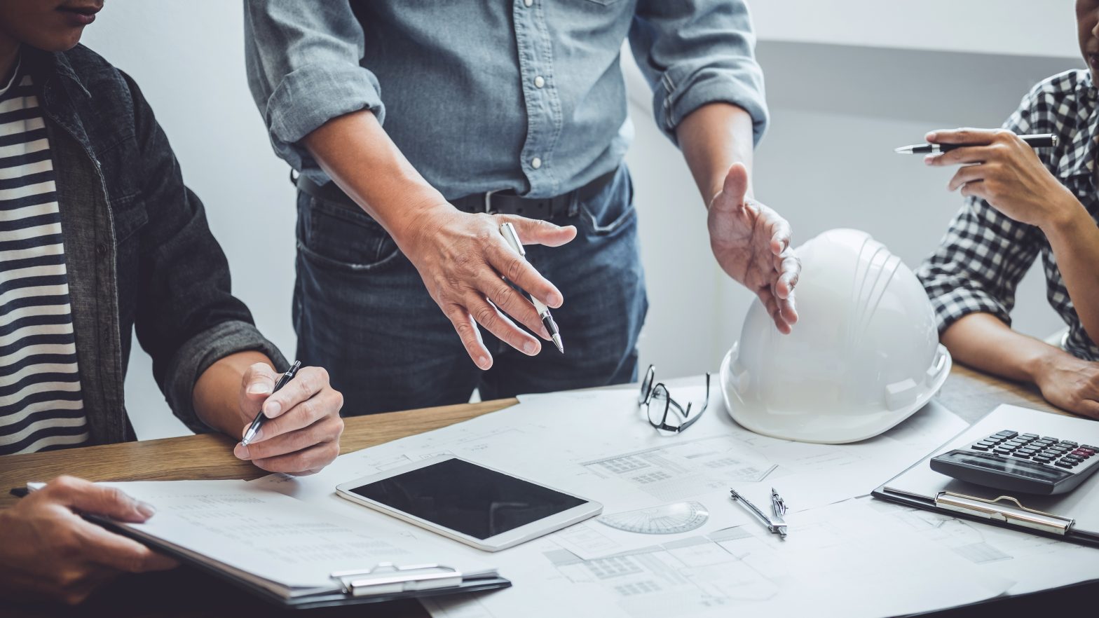 3 people meeting to discuss the architecture and construction of a building