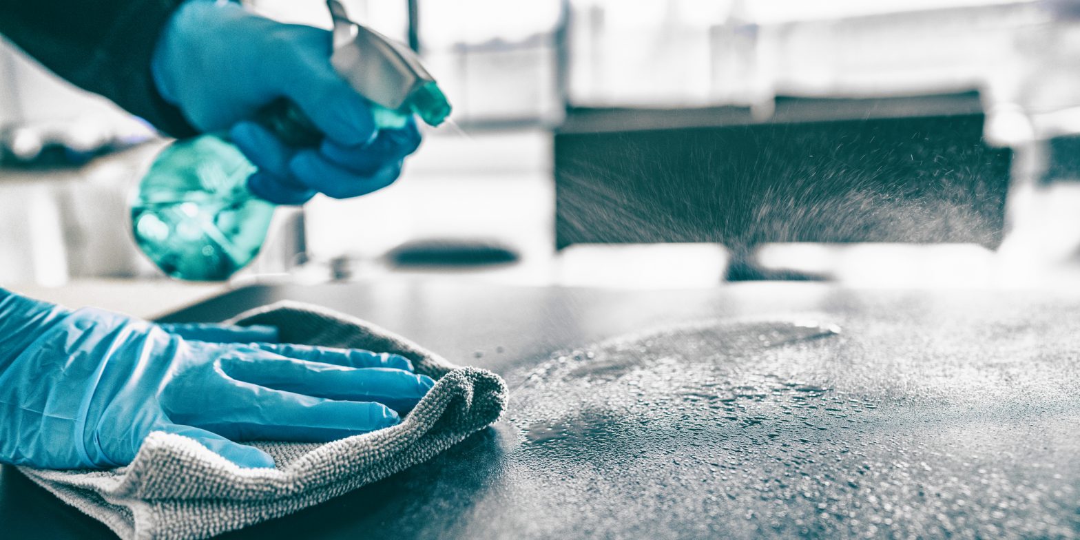 cleaning surface with gloved hands and sanitizer
