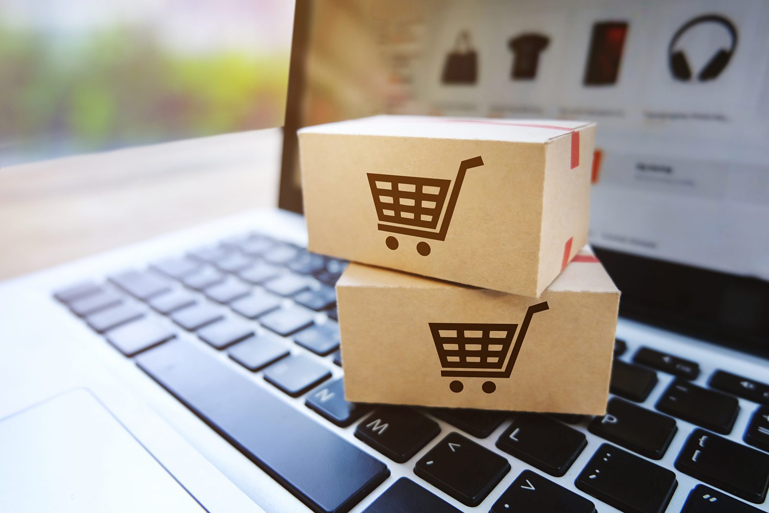 Two cardboard packing boxes placed on the keyboard of a lap top with four different images displayed on the laptop screen.