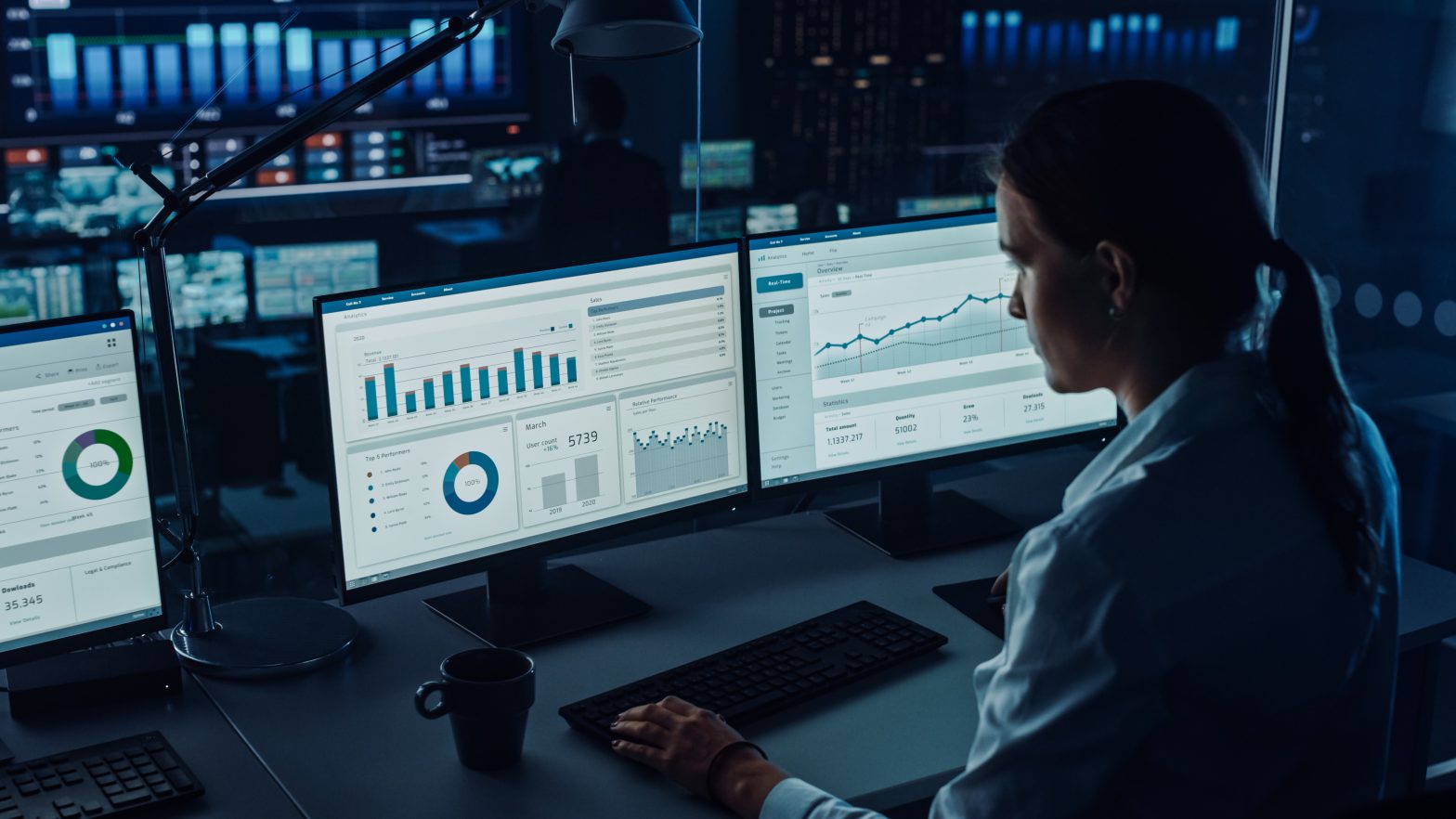 Woman sat at a computer screen showing data and analytics