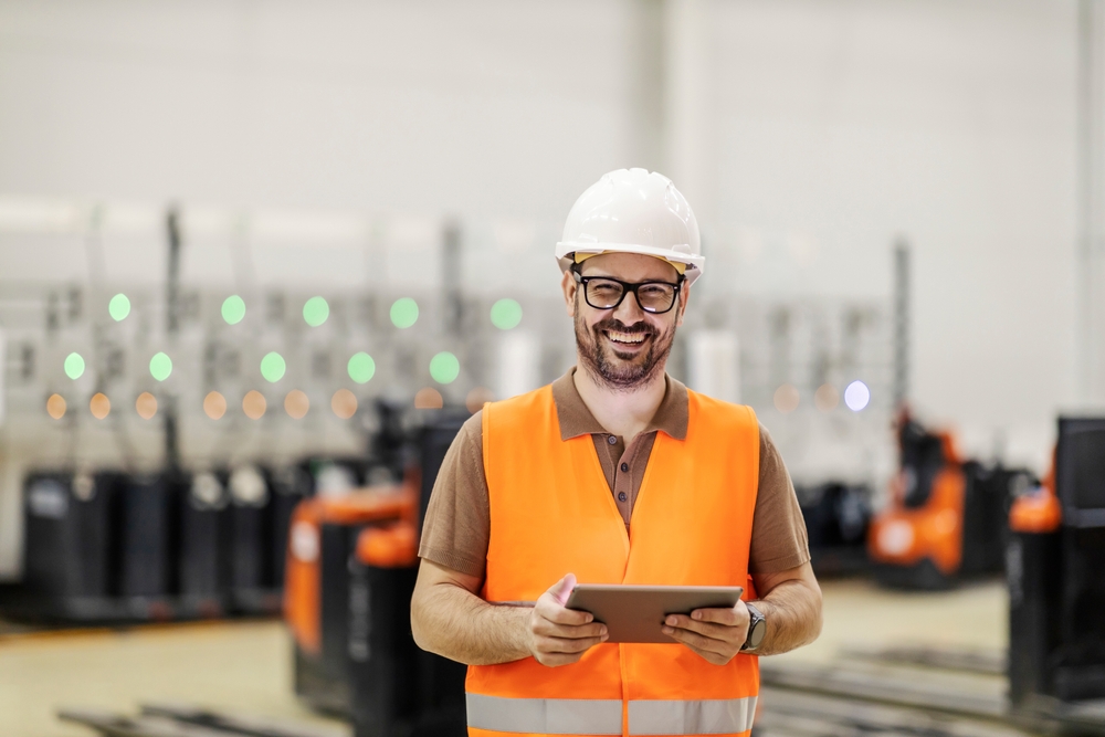 Sustainability in warehouse. A storage manager is standing at forklift charging department and using tablet to control charging.