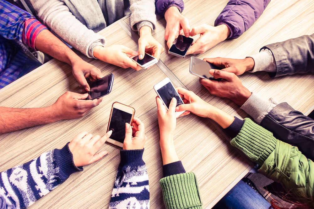 A diverse group of hands in a circle using mobile phones